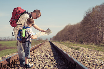 Image showing Father and son walking on the railway at the day time.