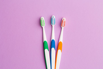 Image showing Photo of three multi-colored toothbrushes