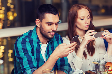 Image showing couple with smartphones dining at restaurant