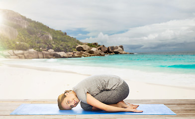 Image showing happy woman doing yoga in child pose on beach