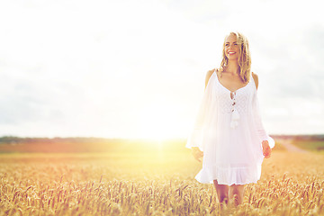 Image showing smiling young woman in white dress on cereal field