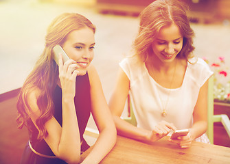 Image showing happy young women with smartphones at outdoor cafe