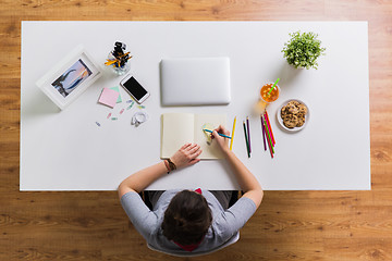 Image showing woman drawing in notebook at home office