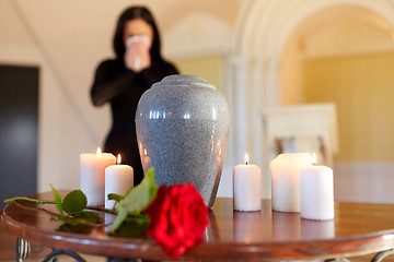 Image showing cremation urn and woman crying in church