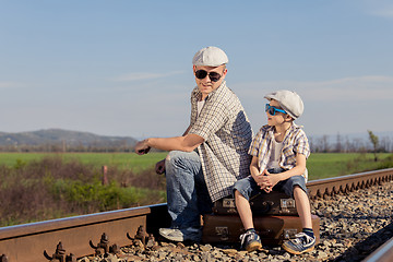 Image showing Father and son walking on the railway at the day time.