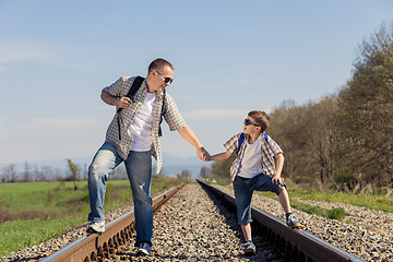 Image showing Father and son walking on the railway at the day time.