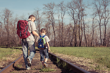 Image showing Father and son walking on the railway at the day time.