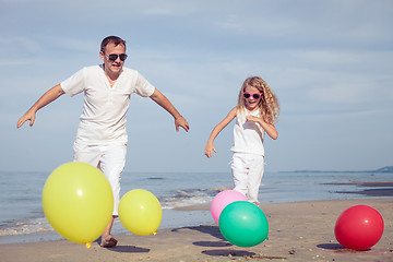 Image showing Father and daughter  playing with balloons on the beach at the d