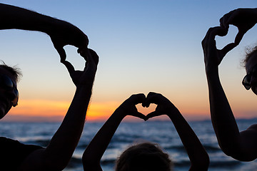 Image showing Silhouette of happy family who playing on the beach at the sunse