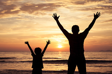 Image showing Father and son playing on the beach at the sunset time.