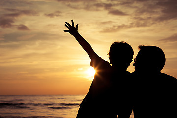 Image showing Father and son playing on the beach at the sunset time.