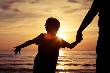 Image showing Father and son playing on the beach at the sunset time.