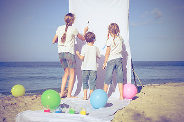 Image showing Two sisters and brother playing on the beach at the day time.