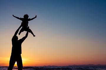 Image showing Father and son playing on the beach at the sunset time.