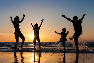 Image showing Silhouette of happy family who playing on the beach at the sunse