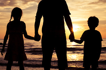 Image showing Father and children playing on the beach at the sunset time.