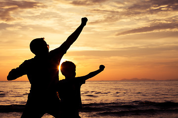Image showing Father and son playing on the beach at the sunset time.