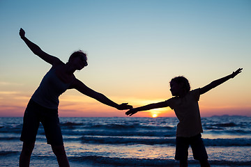 Image showing Mother and daughter playing on the beach at the sunset time.