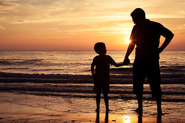 Image showing Father and son playing on the beach at the sunset time.