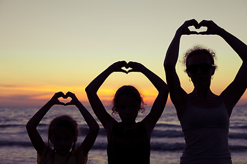 Image showing Mother and daughters playing on the beach at the sunset time.