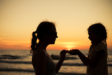 Image showing Mother and daughter playing on the beach at the sunset time.