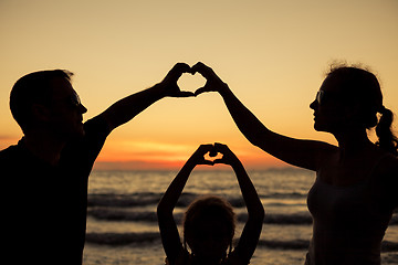 Image showing Silhouette of happy family who playing on the beach at the sunse