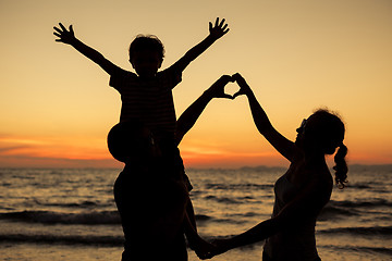 Image showing Silhouette of happy family who playing on the beach at the sunse