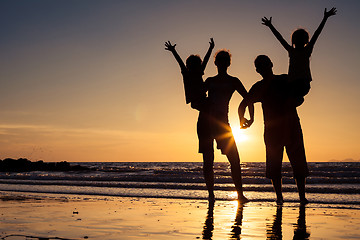 Image showing Silhouette of happy family who standing on the beach at the suns