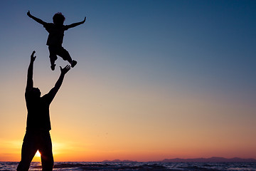 Image showing Father and son playing on the beach at the sunset time.