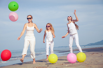 Image showing Mother and daughters  playing with balloons on the beach at the 