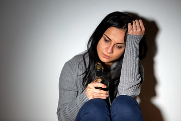 Image showing unhappy drunk crying woman with bottle of alcohol