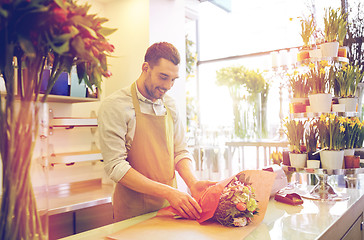 Image showing florist wrapping flowers in paper at flower shop