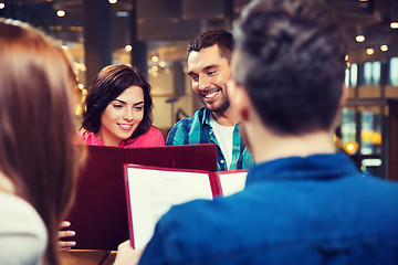 Image showing smiling couple with friends and menu at restaurant