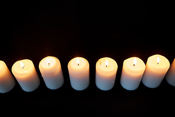 Image showing candles burning in darkness over black background