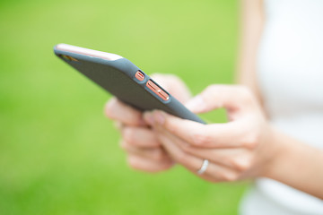 Image showing Woman hold a mobile phone over green plant background