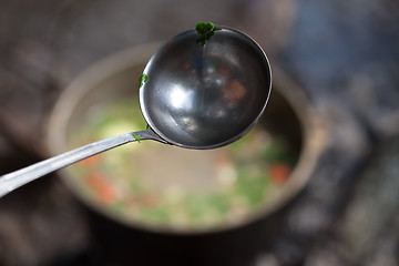 Image showing Wet metal ladle (spoon) with pieces of coriander leaf