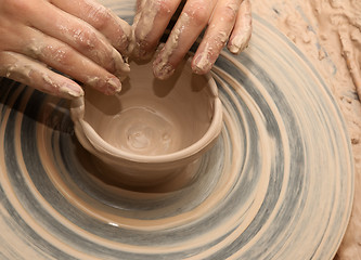 Image showing Woman in process of making clay bowl on pottery wheel