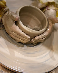 Image showing Young girl in process of making clay bowl on pottery wheel