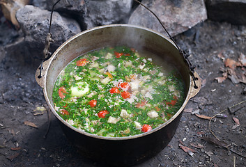 Image showing Freshly cooked hot soup in sooty cauldron at camping