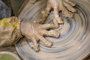 Image showing Hands of young girl in clay on pottery wheel