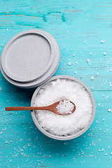 Image showing Sea salt in an stone bowl with small wooden spoon on a blue wooden table