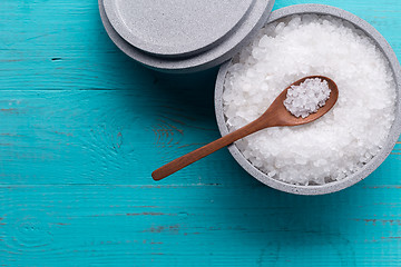 Image showing Sea salt in an stone bowl with small wooden spoon on a blue wooden table