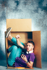 Image showing Introvert concept. Man sitting inside box and working with phone