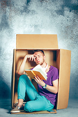 Image showing Introvert concept. Man sitting inside box and reading book