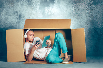 Image showing Introvert concept. Man sitting inside box and working with phone