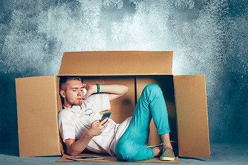 Image showing Introvert concept. Man sitting inside box and working with phone