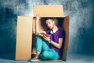 Image showing Introvert concept. Man sitting inside box and reading book