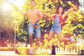 Image showing happy teenage couple jumping at summer park