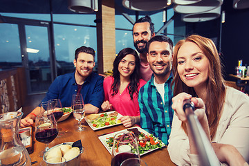 Image showing friends picturing by selfie stick at restaurant