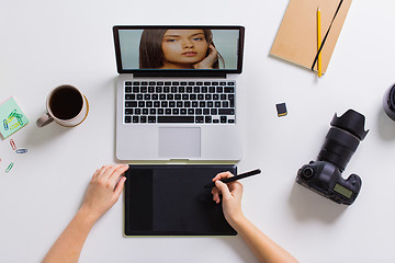 Image showing woman with camera working on laptop at table